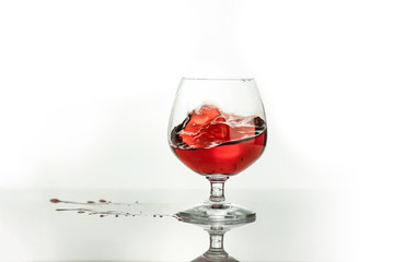 Red wine splashing out of a glass, isolated on white. Concept: alcoholic drinks