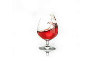 Red wine splashing out of a glass, isolated on white. Concept: alcoholic drinks