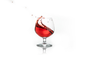 Red wine splashing out of a glass, isolated on white. Concept: alcoholic drinks