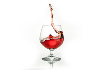 Red wine splashing out of a glass, isolated on white. Concept: alcoholic drinks