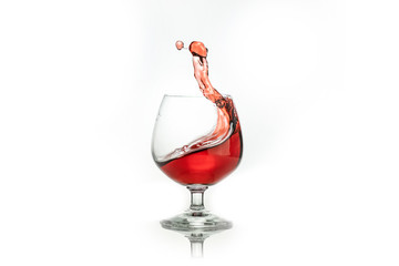 Red wine splashing out of a glass, isolated on white. Concept: alcoholic drinks