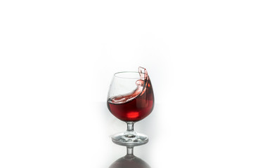 Red wine splashing out of a glass, isolated on white. Concept: alcoholic drinks