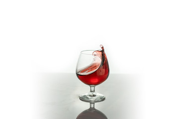 Red wine splashing out of a glass, isolated on white. Concept: alcoholic drinks