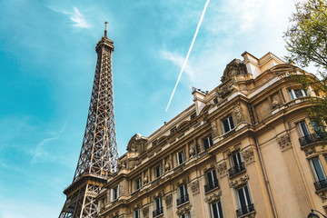 Fototapeta na wymiar City street in Paris, France. Eiffel Tower and old french building in summer. Condensation trail of jet plane on blue sky.
