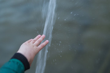 The hand of the child under a strong stream of water.