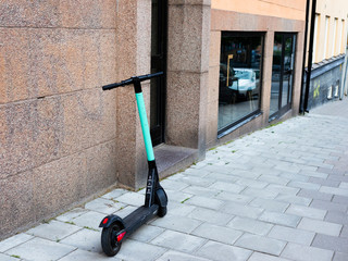 A Tier electric scooter (elscooter) leans on a stone wall in central Stockholm. © Anders