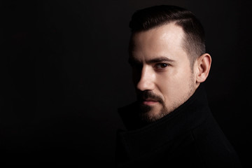 Fototapeta premium Handsome bearded man in a black coat. Black background.