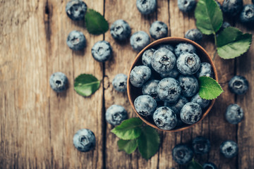 Obraz na płótnie Canvas Freshly picked blueberries in wooden bowl on wooden background. Healthy eating and nutrition.