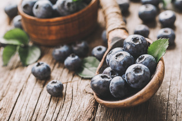 Blueberries in wooden spoon on old wood table. Healthy eating and nutrition concept.