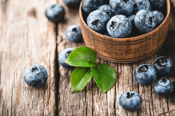Freshly picked blueberries in wooden bowl on wooden background. Healthy eating and nutrition.