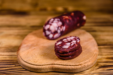 Cutting board with sliced salami sausage on a wooden table