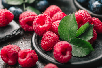 Freshly picked raspberries in bowl on old metal background. Healthy eating and nutrition.