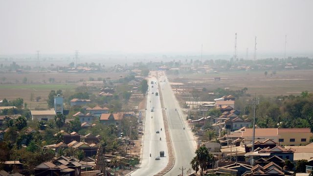 Upper view of the main road going through small town under dusty grey skies ( time lapse)