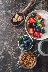 Healthy breakfast with granola, yogurt, fruits, berries on dark metal background. Summer homemade breakfast.