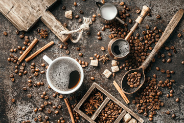 Coffee cup, sugar, milk and coffee beans on dark background.