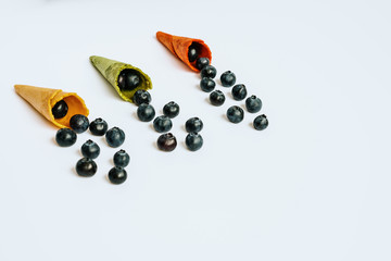 Ripe blueberries lined up in an empty ice cream cone, healthy desserts in summer, isolated on white background with copy space.