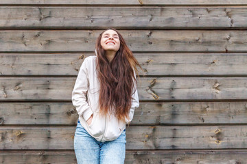 Happy girl smiling. Beauty portrait young happy positive laughing brunette woman on wooden wall background. European woman. Positive human emotion facial expression body language