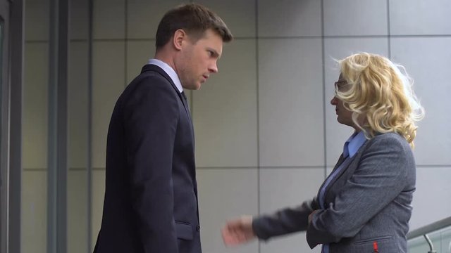 Elderly female CEO annoyed by lateness of young employee, disciplinary action