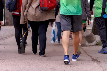 Group of people walk on the sidewalk, some with sports clothes