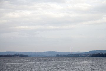 Belgrade under the rain seen from Zemun, with an industrial chimney in background in front, on the Danube river, and seagulls flying in front