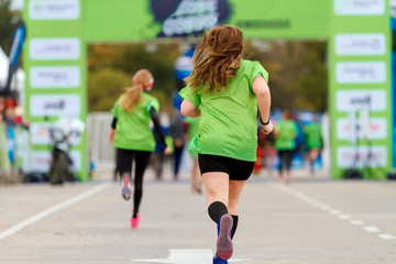 Several women seen from behind run towards the final line in a marathon
