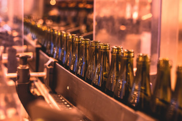 View of glass bottles on the conveyor belt, bottle necks on the production line, brewery equipment,...
