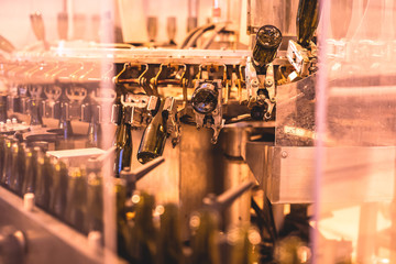 View of glass bottles on the conveyor belt, bottle necks on the production line, brewery equipment, inside wine factory, process of alcohol liquor manufacture production