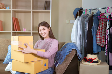 Attractive beautiful asian woman holding boxes or packages, ready sending to her customers. Charming beautiful young girl feel happiness because she can earn a lots of money by selling goods at home