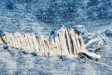 Denim texture.Blue jeans with threads and holes for the background