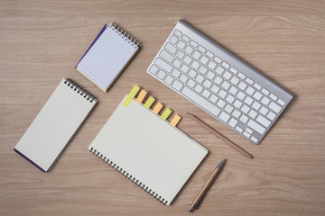 Workspace with diary or notebook and clipboard, keyboard, pencil, sticky notes on wooden background