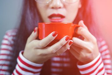 Asian women wearing glasses are holding red coffee