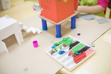 Craft lesson in kindergarten. Model of paper house glued out of paper and colored by child.
