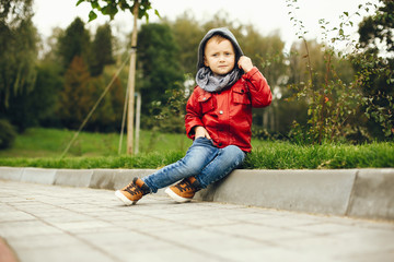 Fototapeta premium Cute little boy in a park. Child playing with a skate.