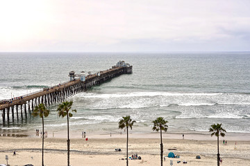 Fototapeta premium OCEANSIDE, CALIFORNIA - 2 JUNE 2019: Oceanside sea view and pier bridge playground and surfboard 