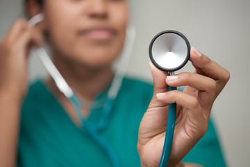A female healthcare professional taking a reading using a stethoscope and carefully listening to...