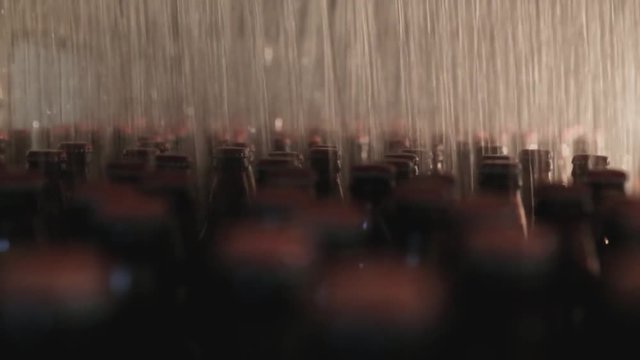 Glass bottles standing on a table. They are being cleaned with water.