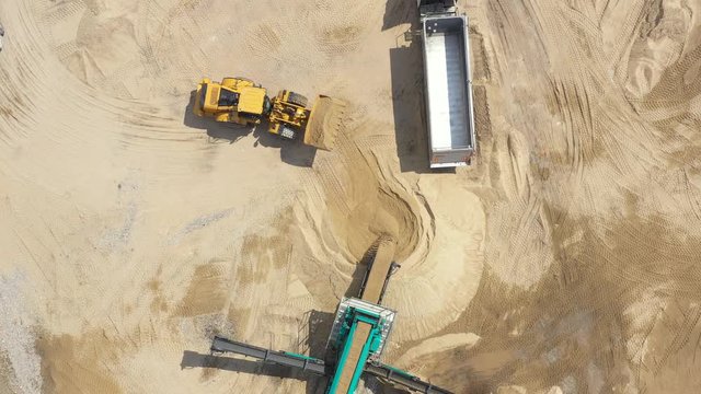 Aerial view loading bulldozer in open air quarry. Sand mining industry. Bulldozer machine. Crawler bulldozer moving at sand mine. Mining machinery working at sand quarry. Drone view