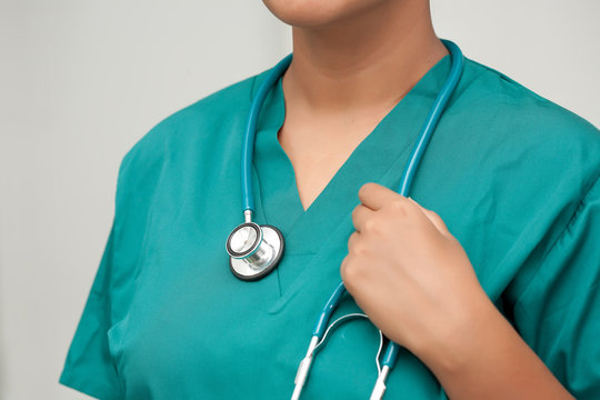 A closeup of a registered nurse with modern teal scrubs and holding a stethoscope.