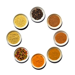 Saucer's dish with black pepper peas, cinnamon, red pepper, curry, turmeric, granulated dried sweet pepper, mustard, sesame seeds isolated on white background