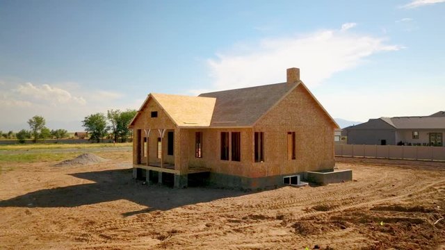 A drone shot pushing in on a recently framed and walled home in the process of a new house getting built.