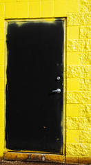 Black door on badly painted yellow walls