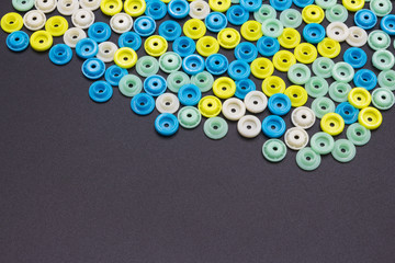 Many small colored round hollow plastic buckles are placed on top of a black background to form a beautiful artistic background