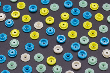 Fototapeta premium Colored round hollow plastic buckles neatly arranged into a beautiful colored grain background