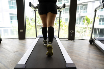 Female legs running on indoor treadmill with bright building background