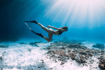 Free diver glides over sandy sea with fins. Freediving in blue ocean