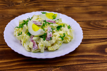 Salad with chinese cabbage, onion, sausage, eggs and mayonnaise on wooden table