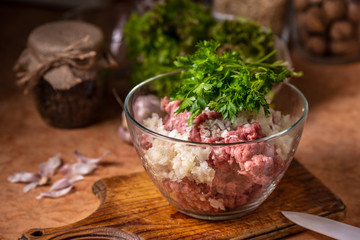 Minced meat with chopped onion and parsley in a glass plate.