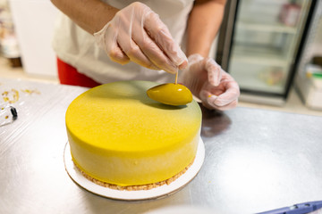 Pastry chef decorates Modern european cake. Mousse dessert covered with yellow velour. Sweet dessert and tea party. French cuisine. Flowers theme. Copy space