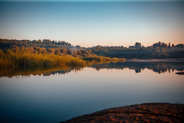 beautiful sunset on the river bank in the summer evening