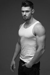 Naklejka premium young man with a beard. A man in a t-shirt. Male portrait on a gray background. Stylish man. black and white photo. Sports man. male fitness model. studio portrait